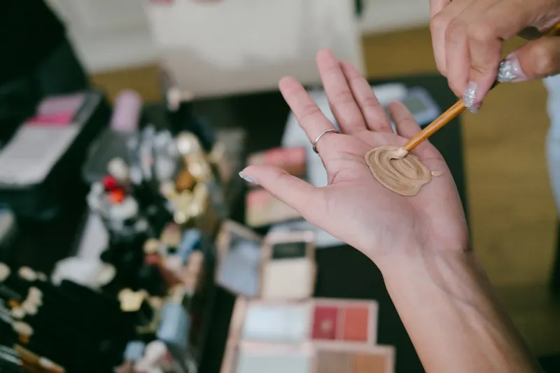 Makeup artist testing foundation shade on hand.